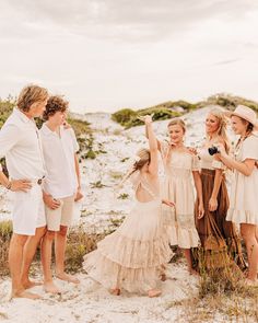 a group of people standing next to each other on top of a sandy beach covered in grass