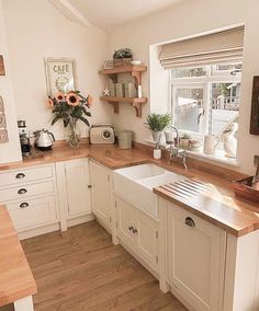 a kitchen with white cabinets and wooden counter tops, sunflowers on the window sill