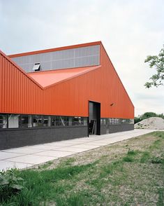 an orange and black building sitting on top of a lush green field