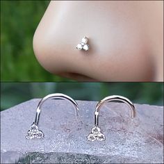 a pair of silver nose piercings with flowers on the top and bottom of them