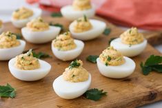 deviled eggs are arranged on a cutting board with garnish and parsley