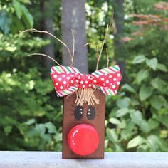 a wooden reindeer head with a red nose and polka dot bow