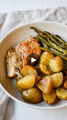 a white bowl filled with potatoes and meat next to green beans on top of a table