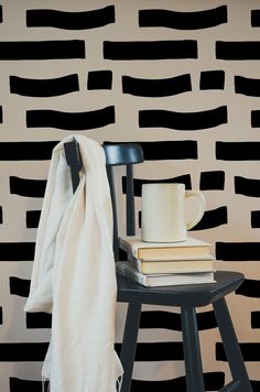 a stack of books sitting on top of a wooden table next to a black and white wall