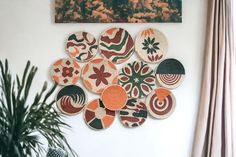 a wall hanging with several woven plates on it and a plant in the foreground