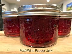 three jars filled with red liquid sitting on top of a wooden table