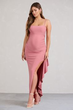 a pregnant woman wearing a pink dress and high slited heels, posing for the camera