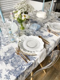 a table set with plates, silverware and flowers in vases on top of it