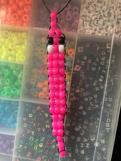 a pink beaded bug is sitting in a plastic box with letters and numbers on it