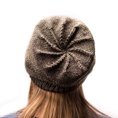 the back of a woman's head wearing a knitted hat with a knot on it