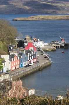 there are many houses on the water by the shore and boats in the water behind them