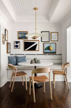 a dining room table with chairs and pictures on the wall above it, along with other furniture