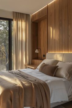 a large bed sitting next to a window in a room with wooden paneled walls