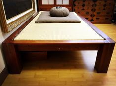 a bed with a pillow on top of it in front of a wooden dresser and mirror