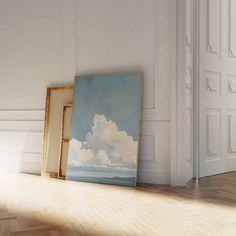 an empty room with two frames on the floor and a painting in front of it