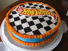 a hot wheels cake is sitting on a white plate with orange and blue icing