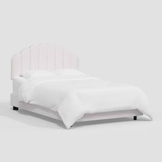 a bed with white linens and black legs on the headboard, in front of a gray background