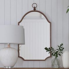 a mirror sitting on top of a wooden shelf next to a lamp and vases