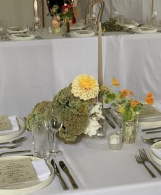 the table is set with silverware, flowers and place settings for two people to sit at