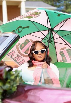 a woman holding an umbrella in front of a car with flowers on the side walk