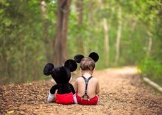 two children sitting on the ground with mickey and minnie mouse stuffed animals