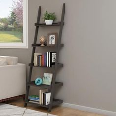 a living room with a white couch and bookshelf in the corner next to a window