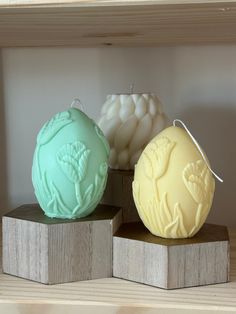 three soap balls sitting on wooden blocks in front of a white and green candle holder