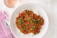 a white bowl filled with rice and beans on top of a pink towel next to a glass of orange juice