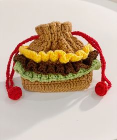 a small crocheted sandwich bag on a white surface with red string around it