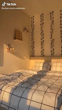 a bed with white sheets and black checkered comforter in a small room that has plants on the wall