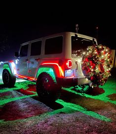 a jeep with christmas lights on it parked in the grass