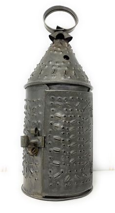 an old fashioned metal lantern with holes on the front and sides, sitting against a white background