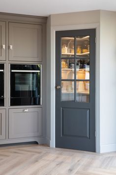 an empty kitchen with gray cabinets and glass front doors that lead into the pantry area