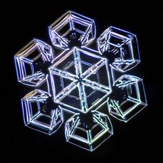 an illuminated snowflake in the dark with cubes on it's sides