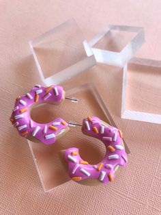 These handmade polymer clay hoop earrings feature donuts with a bite taken out. They are kawaii food inspired, and make a cute, smaller statement for any outfit. | Donut Hoop Earrings, Half Eaten Donut Earrings, Cute Earrings, Kawaii Earrings, Baked Goods Earrings, Donut Jewelry, Statement Earrings Polymer Clay Hoop Earrings, Clay Hoop Earrings, Donut Jewelry, Hoop Earrings Diy, Donut Earrings, Donuts Earrings, Homemade Clay, Food Inspired, Earrings Kawaii