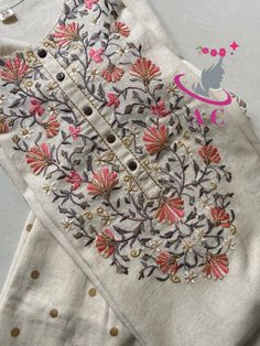 an embroidered blouse with pink flowers and gold dots on the bottom, in front of a white background