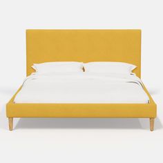 a yellow bed with white sheets and pillows