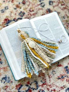 an open book with tassels on top of it sitting on a carpeted floor