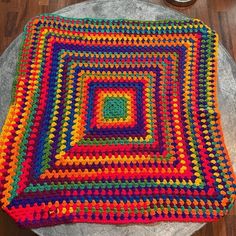 a multicolored crocheted blanket sitting on top of a table