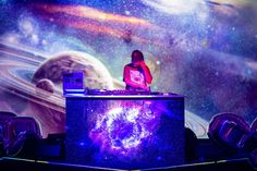 a dj performing in front of an image of the solar system and its planets on display