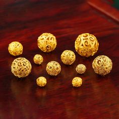 six gold balls sitting on top of a wooden table next to each other with intricate designs