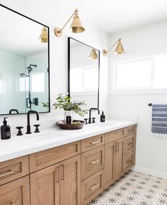 a bathroom with two sinks, mirrors and lights on the wall above them is shown