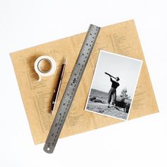 an old photo with a ruler, tape and pen on it next to a cup of coffee