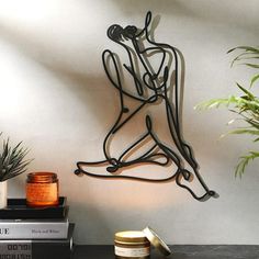 a metal sculpture sitting on top of a table next to a potted plant and books