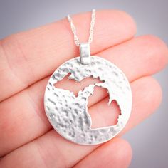 Flaunt your Michigan pride with this lovely sterling silver pendant.  Both peninsulas of Michigan are cut out of a large silver circle that has been textured to catch the light.This pendant measures approximately 1 1/8th inches in diameter, not including the bail.  Each pendant comes with a sterling silver chain at no extra charge. Please specify 16, 18, or 20 inches long for the chain.  If in doubt, 18 inch chains work well for most people. The pendant will come to you gift boxed, whether it is Etched Sterling Silver Round Disc Jewelry, Etched Sterling Silver Round Pendant Jewelry, Sterling Silver Coin Pendant Jewelry, Hammered Sterling Silver Medallion Jewelry, Sterling Silver Hammered Medallion Jewelry, Silver Circle, Sterling Silver Chain, Sterling Silver Pendant, Sterling Silver Chains