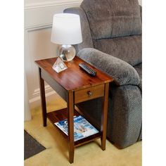 a small wooden table with a remote control on it next to a recliner chair