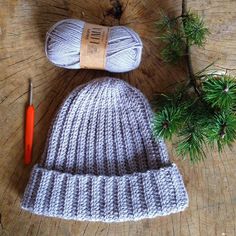 a crocheted hat and ball of yarn sitting on top of a tree stump