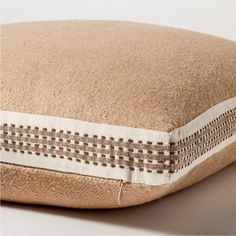 a close up of a pillow on a white surface with brown and white trimmings