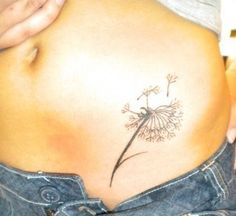 a woman's stomach with a dandelion tattoo on it