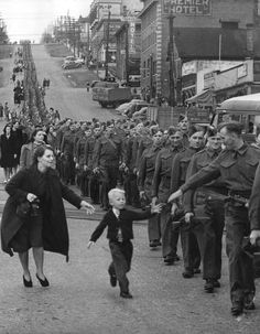 a woman walking down a street holding the hand of a small child in front of a crowd of people